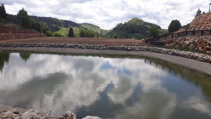 Lacul artificial și, în spatele său, noul teren de fotbal din ... vârful muntelui